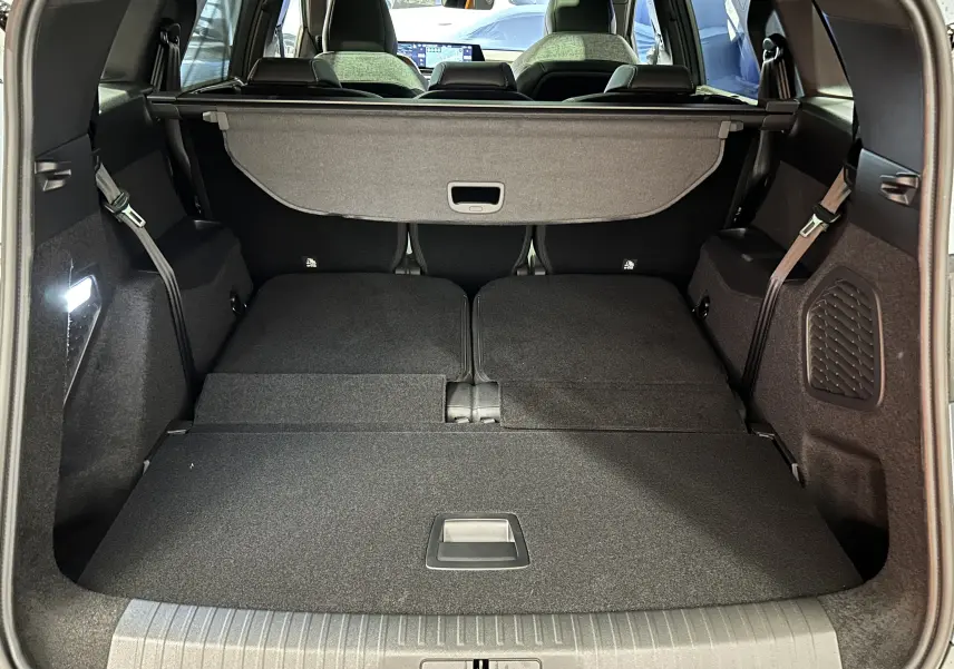 Vue depuis le coffre du Peugeot 5008 bleu Ingaro, montrant l’espace de chargement avec banquette arrière rabattue et cache-bagages.