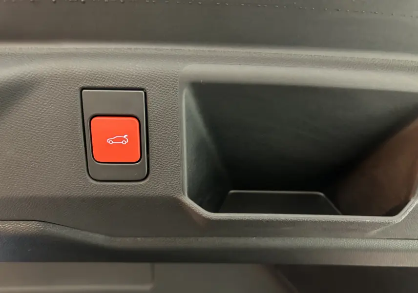 Bouton rouge d'ouverture électrique du hayon sur le panneau intérieur d'un Peugeot 5008 bleu Ingaro.