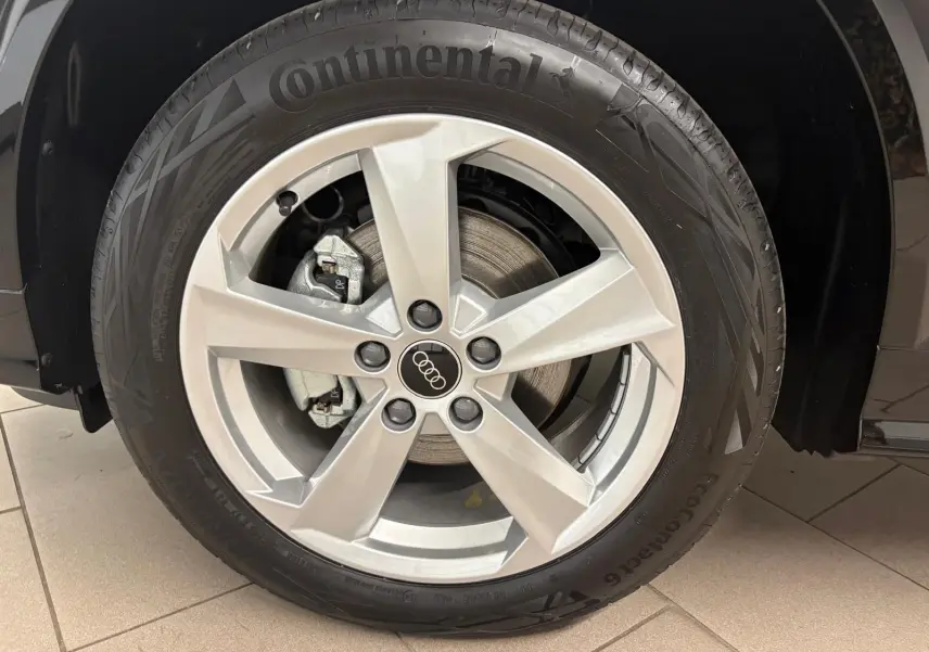 Gros plan sur la roue avant droite d’un Audi Q2 35 TFSI 150 S tronic 7 S line noir mythic avec jante alliage argentée.