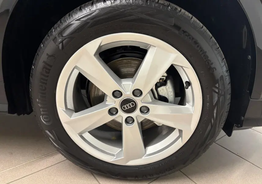 Gros plan sur la roue avant droite d’un Audi Q2 Noir Mythic avec jante alliage 5 branches et pneu Continental.