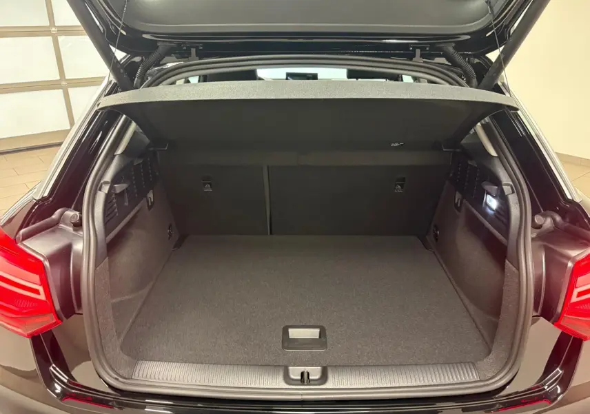 Coffre ouvert vu de l'arrière d'un Audi Q2 35 TFSI S Line 2026 en noir Mythic, avec hayon électrique relevé.