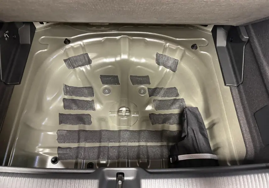 Coffre ouvert de l'Audi Q2 35 TFSI 150 S tronic 7 S line noir Mythic, montrant le logement vide de la roue de secours.