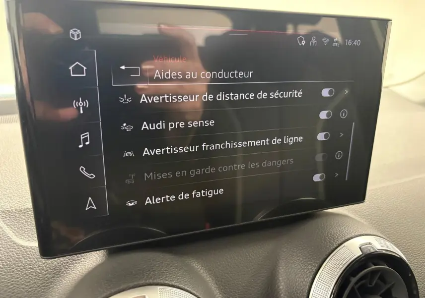 Écran tactile intérieur de l'Audi Q2 35 TFSI S Line affichant les aides à la conduite, vue rapprochée du tableau de bord.
