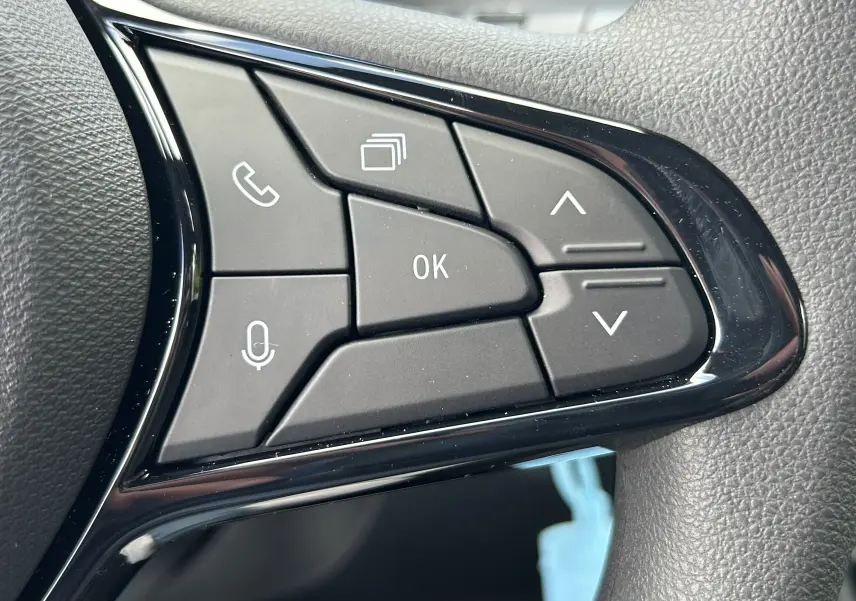 Gros plan sur les commandes multifonctions noires du volant côté gauche du Renault Master blanc, avec boutons téléphone et navigation.