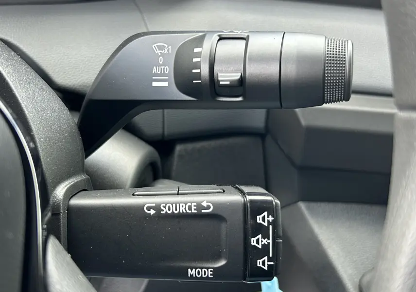 Gros plan sur les commandes au volant du Renault Master 2025, boutons noirs avec inscriptions blanches, intérieur gris.