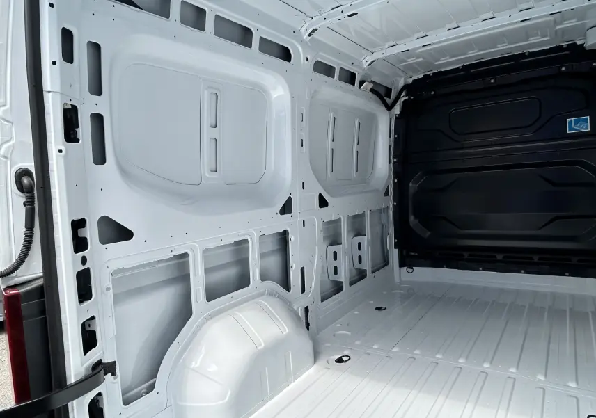 Vue intérieure arrière du fourgon blanc Renault Master IV L2H2, montrant la structure métallique nue et l'espace de chargement vide.