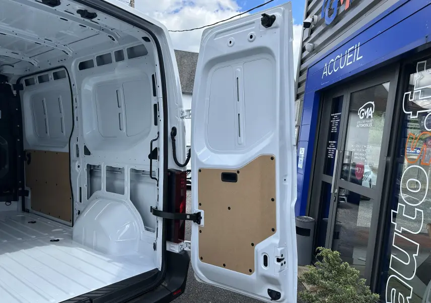 Vue arrière ouverte du Renault Master blanc 2025, montrant l’intérieur vide et les portes arrière avec panneaux de protection en bois.