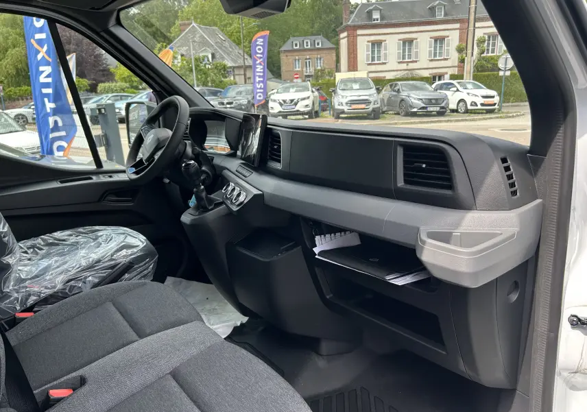 Intérieur côté passager du Renault Master blanc 2025, montrant tableau de bord et sièges en tissu gris.