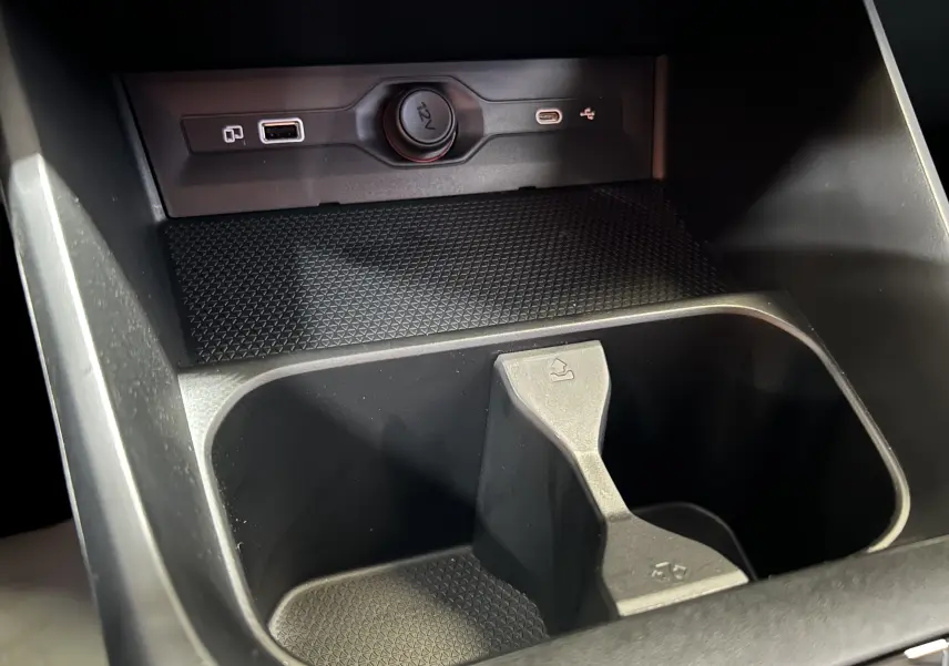 Gros plan sur la console centrale noire du MG3 Hybrid+ 195 Luxury avec prises USB et allume-cigare 12V visibles.