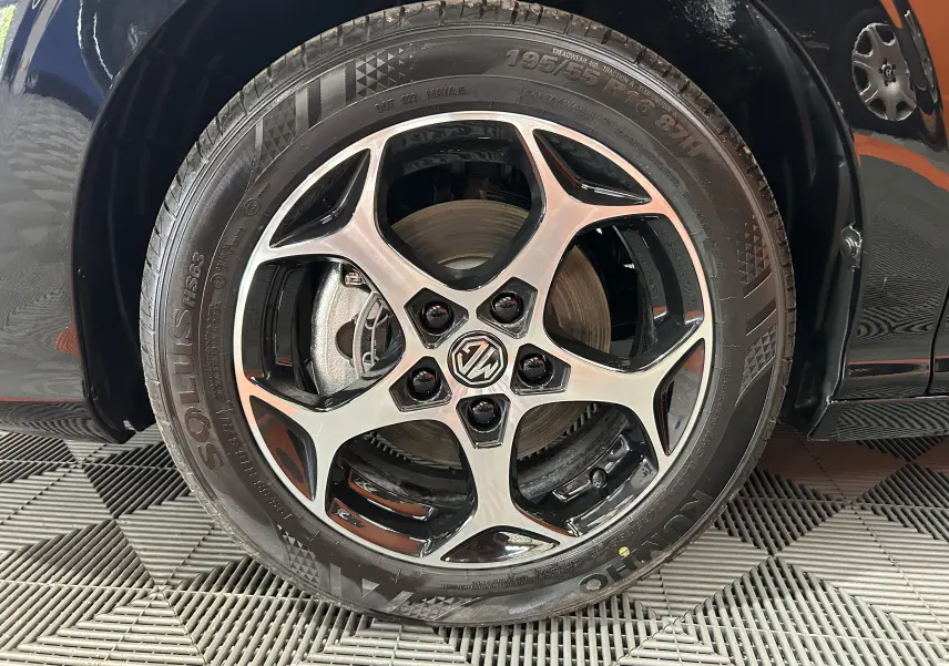 Gros plan sur la roue avant droite du MG3 Hybrid+ 195 Luxury Pebble Black avec jante alliage bicolore et logo MG central.