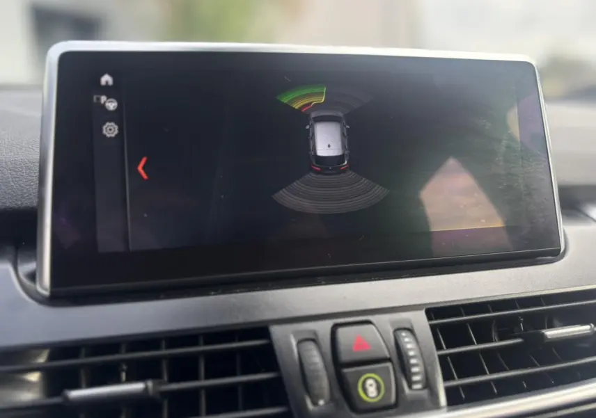 Écran central du tableau de bord montrant l'aide au stationnement avec vue aérienne du véhicule BMW Série 2 Active Tourer.