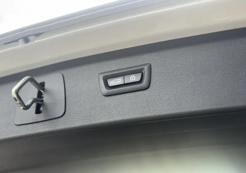 Gros plan sur le hayon blanc de la BMW Série 2 Active Tourer 218dA avec bouton d'ouverture électrique et serrure visible.