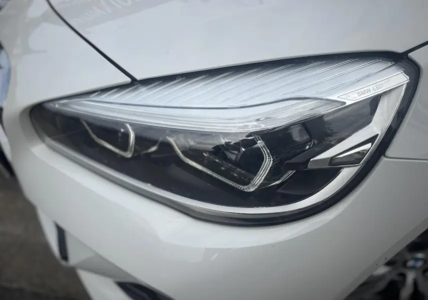 Gros plan sur le phare avant droit blanc d’une BMW Série 2 Active Tourer 218dA M Sport avec éclairage LED distinctif.