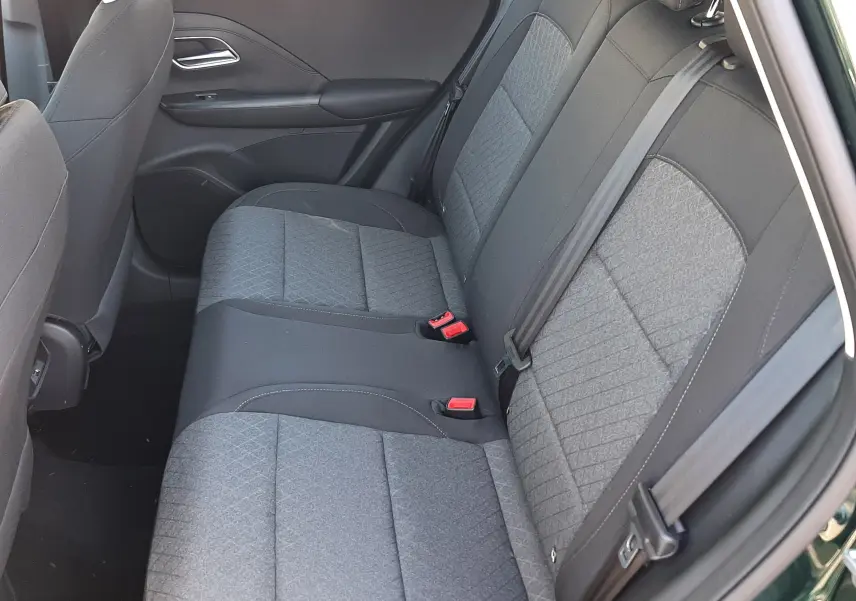 Vue intérieure côté droit des sièges arrière gris tissu du MG Motor ZS 1.5 Hybrid+ 197ch Comfort, portière verte ouverte.
