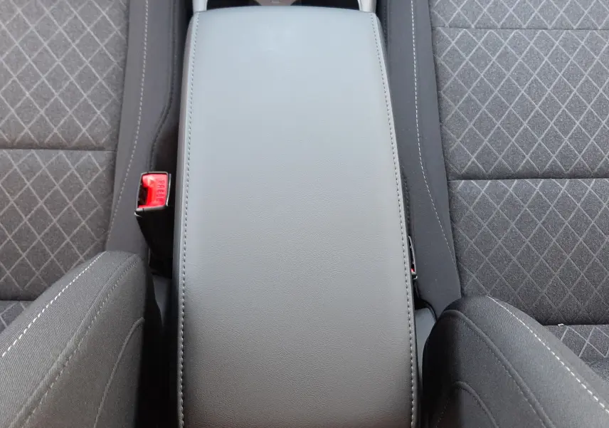 Vue plongeante sur l'accoudoir central gris et les sièges tissu gris à motifs du MG Motor ZS 1.5 Hybrid+ 2026.