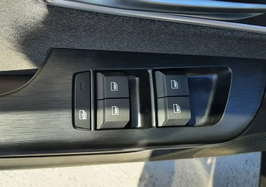Gros plan sur les commandes de lève-vitres côté conducteur de la MG Motor ZS 1.5 Hybrid+ 197ch Comfort, finition noire.