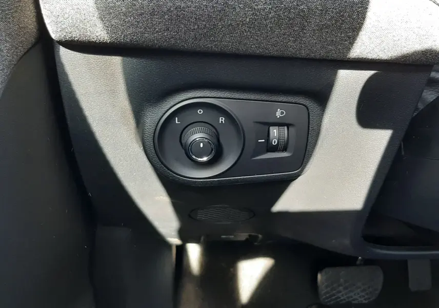 Gros plan sur les commandes de réglage des rétroviseurs et des phares, côté conducteur du MG MOTOR ZS 1.5 Hybrid+ 2026.