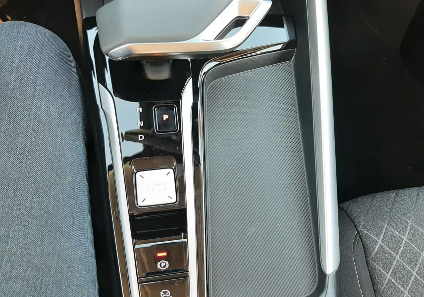 Vue plongeante sur la console centrale noire brillante du MG ZS Emerald Green, avec levier de vitesse automatique et bouton start/stop.