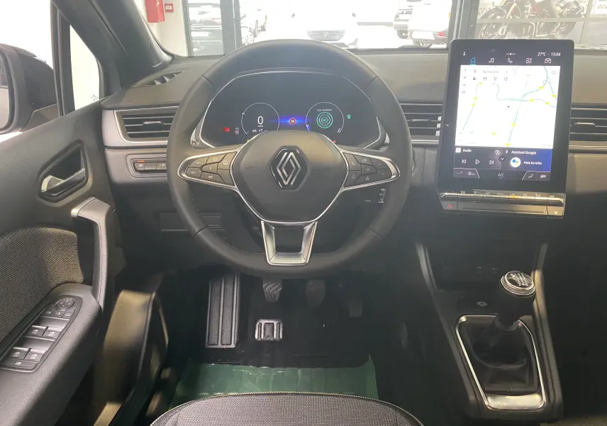 Vue intérieure du poste de conduite du Renault Captur II gris zinc, avec volant multifonction, écran tactile vertical et levier de vitesse manuel.