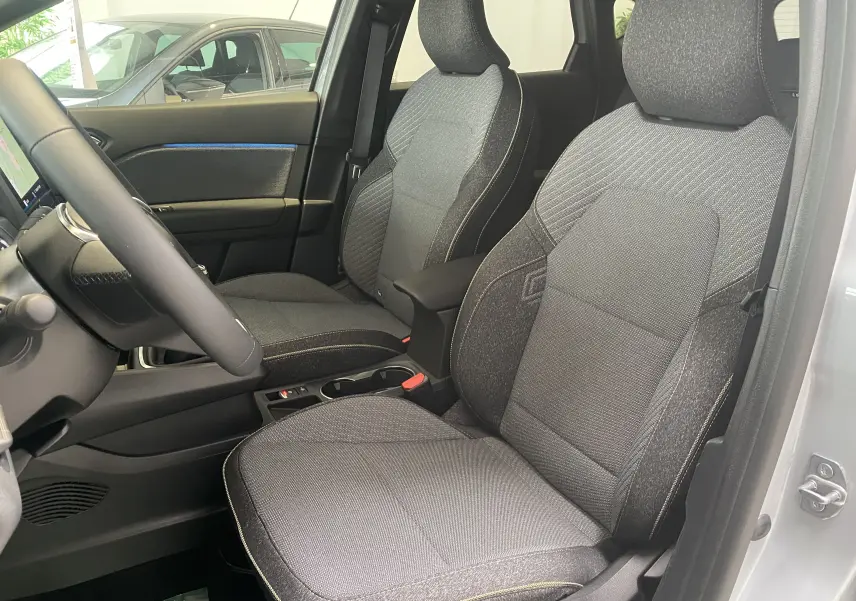 Intérieur du Renault Captur II 2024 en tissu noir, vue côté conducteur avec détails de sièges et console centrale.