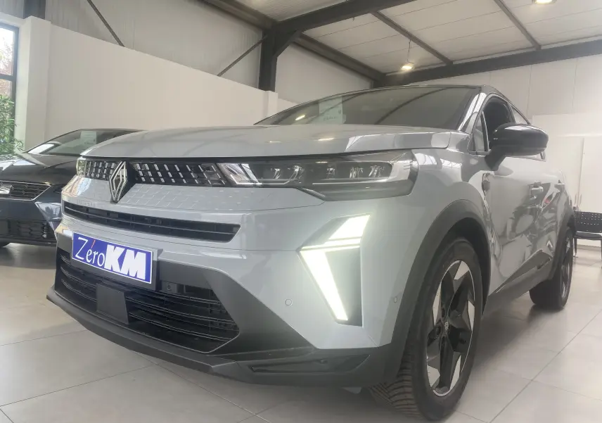 Renault Captur II 1.0 TCE 90CH TECHNO gris zinc métal vu en 3/4 avant droit avec feux LED allumés en showroom.