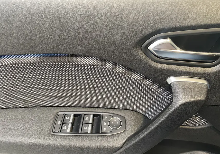 Gros plan sur la portière côté gauche du Renault Captur gris zinc métal, montrant les commandes des vitres et la poignée intérieure.