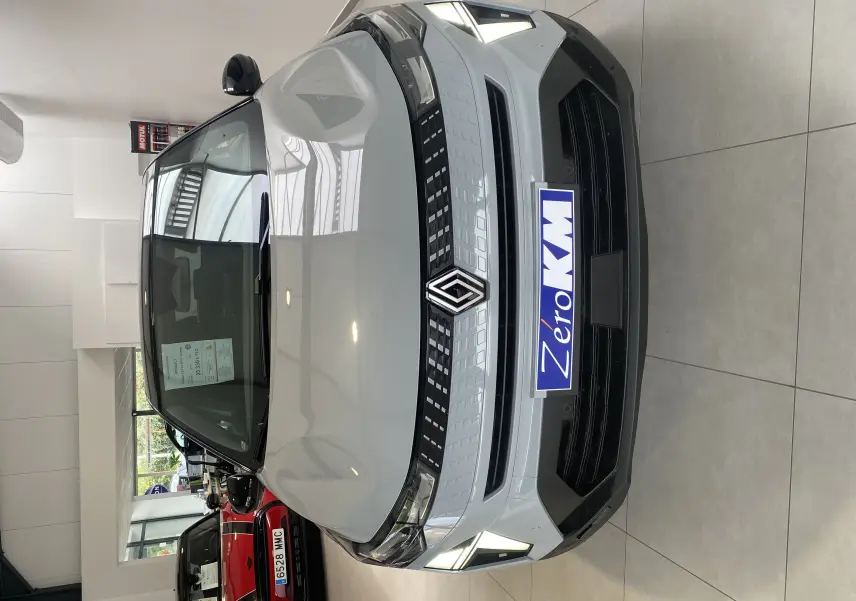 Vue de face d'un Renault Captur II gris zinc métal avec calandre noire et feux LED allumés en showroom.