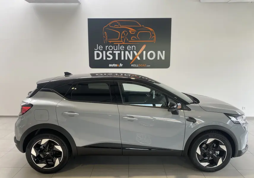 Profil droit du Renault Captur II gris zinc métal avec toit noir et jantes 18 pouces bicolores en showroom.