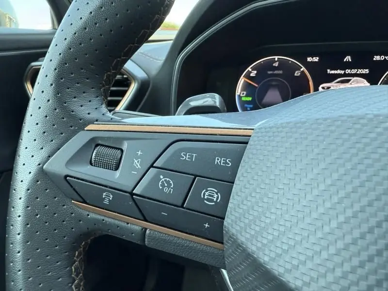 Gros plan sur les commandes du volant perforé du CUPRA Formentor gris 2023, affichage numérique du tableau de bord en arrière-plan.