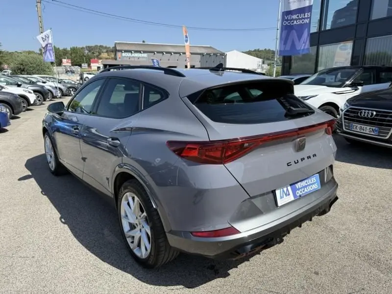 Vue 3/4 arrière droite d'un CUPRA Formentor gris 2023, hybride essence, avec feux arrière reliés et jantes blanches.