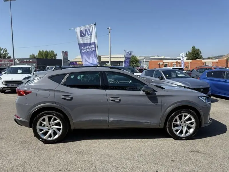 Vue de profil côté gauche d'un CUPRA Formentor gris 2023, version hybride essence, sur un parking en extérieur.