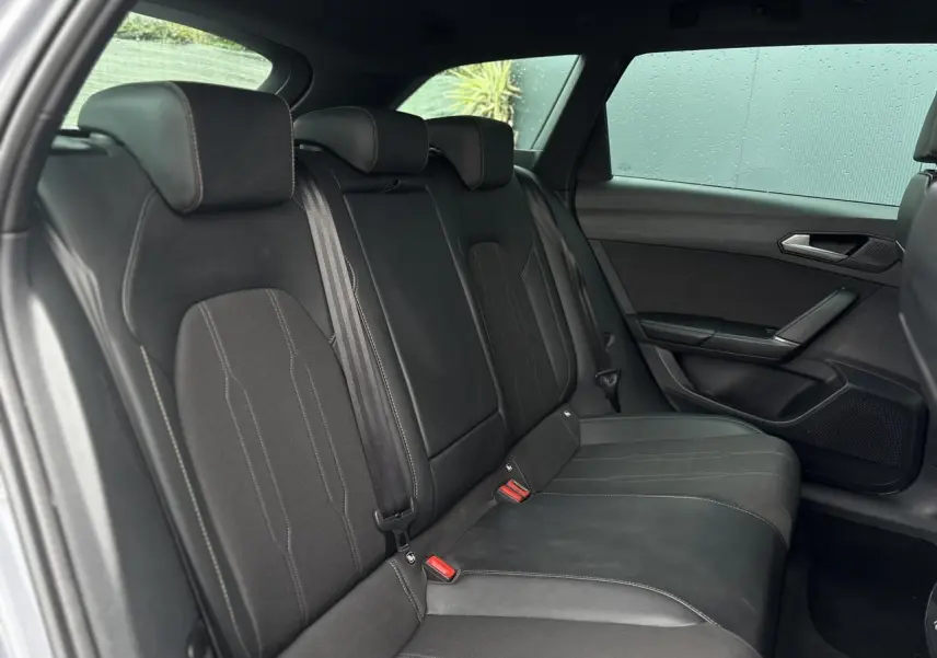 Vue côté droit des sièges arrière noirs en cuir et tissu du CUPRA LEON ST 2025 avec ceinture et appuie-têtes intégrés.