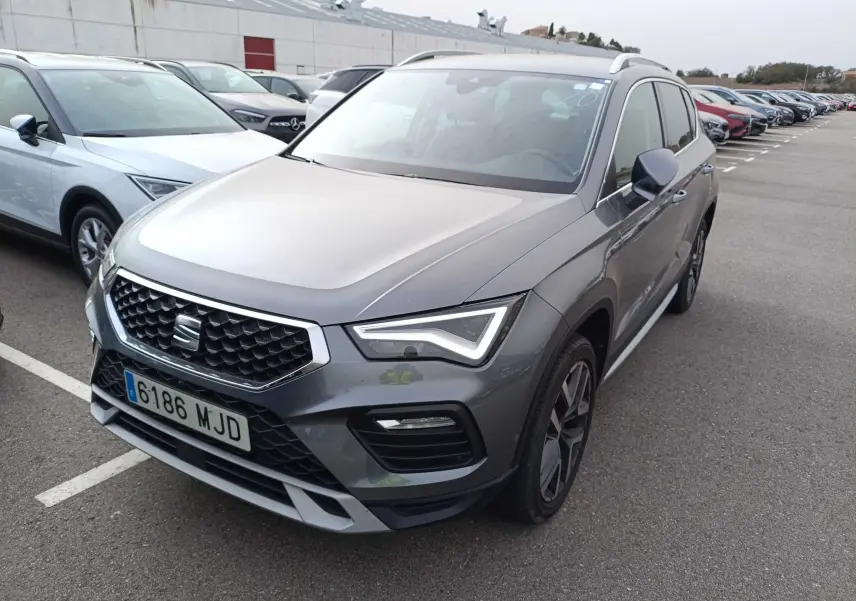 SEAT Ateca gris foncé métal vu en 3/4 avant droit sur un parking, avec calandre et phares LED distinctifs.