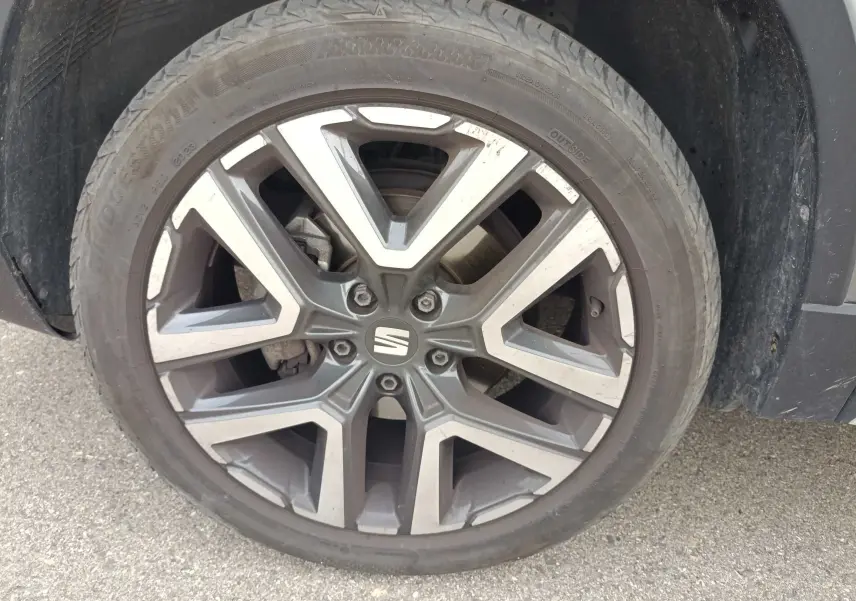 Gros plan sur la jante alliage 18 pouces du SEAT Ateca gris foncé, montrant le logo central et le pneu.