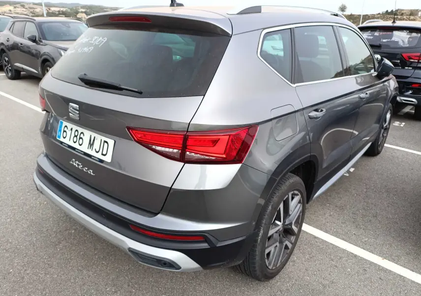 Vue 3/4 arrière droite d'un SEAT Ateca gris foncé métal 2023 avec feux arrière LED et jantes alliage.