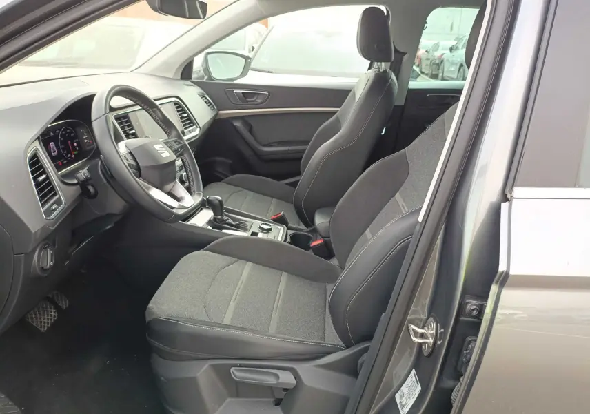 Vue intérieure côté conducteur du SEAT Ateca gris foncé 2023, montrant les sièges tissu et cuir, volant multifonction et console centrale.