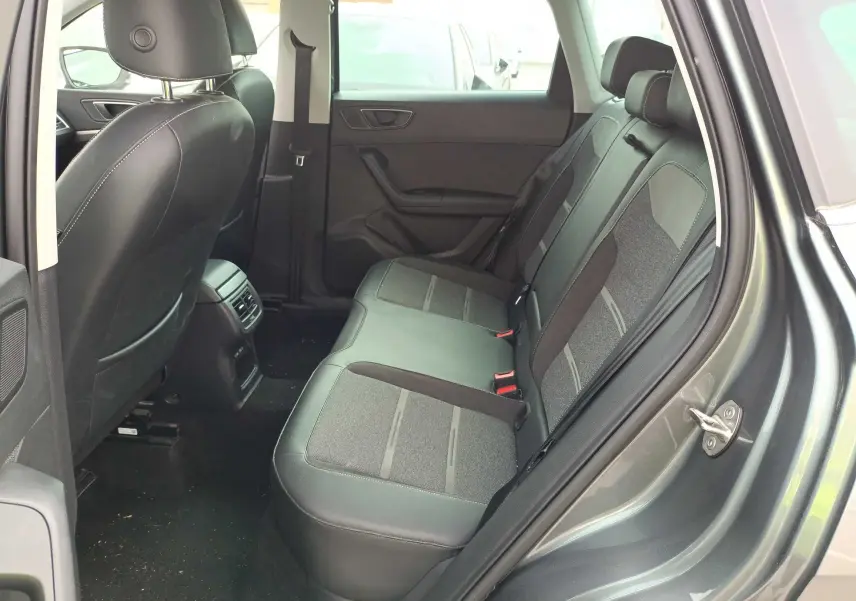 Vue côté droit de l’habitacle arrière du SEAT Ateca gris foncé, montrant les sièges bi-matière et les aérations centrales.