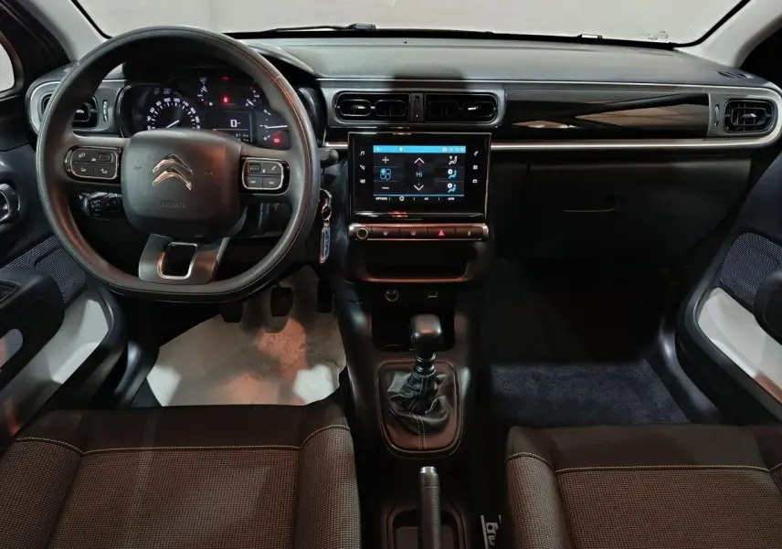 Vue intérieure avant du Citroën C3 2024 gris foncé, avec tableau de bord central tactile et volant multifonctions.
