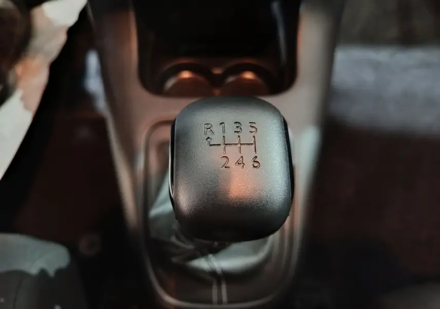 Gros plan sur le levier de vitesses manuel noir de la Citroën C3 2024 BlueHDi 100 BVM PLUS, intérieur sombre.