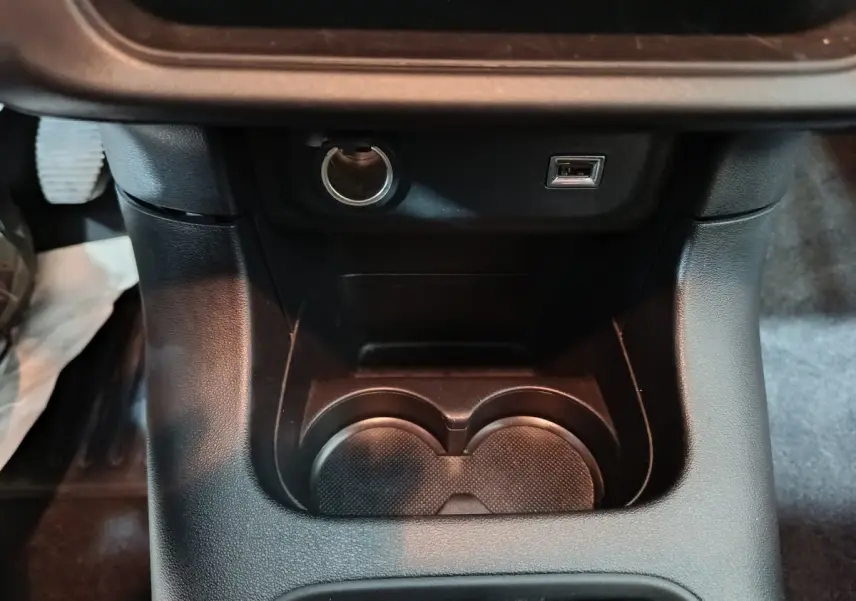 Vue rapprochée de la console centrale noire avec prise 12V et port USB de la Citroën C3 2024 gris foncé.