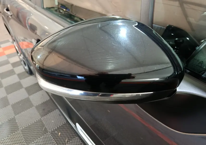 Gros plan sur le rétroviseur droit noir brillant d'une Citroën C3 gris foncé, avec clignotant intégré.