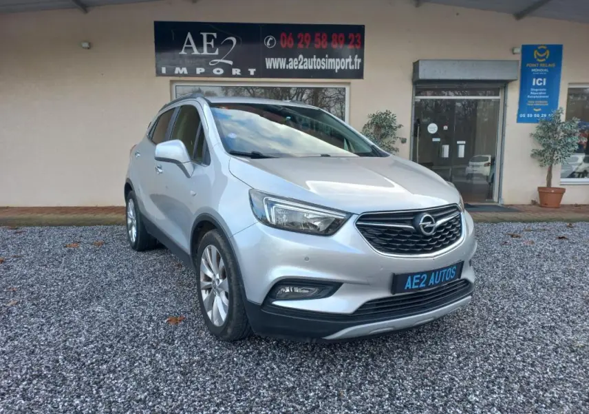 Opel Mokka X gris 2017 en 3/4 avant droit, avec calandre noire et jantes alliage visibles.