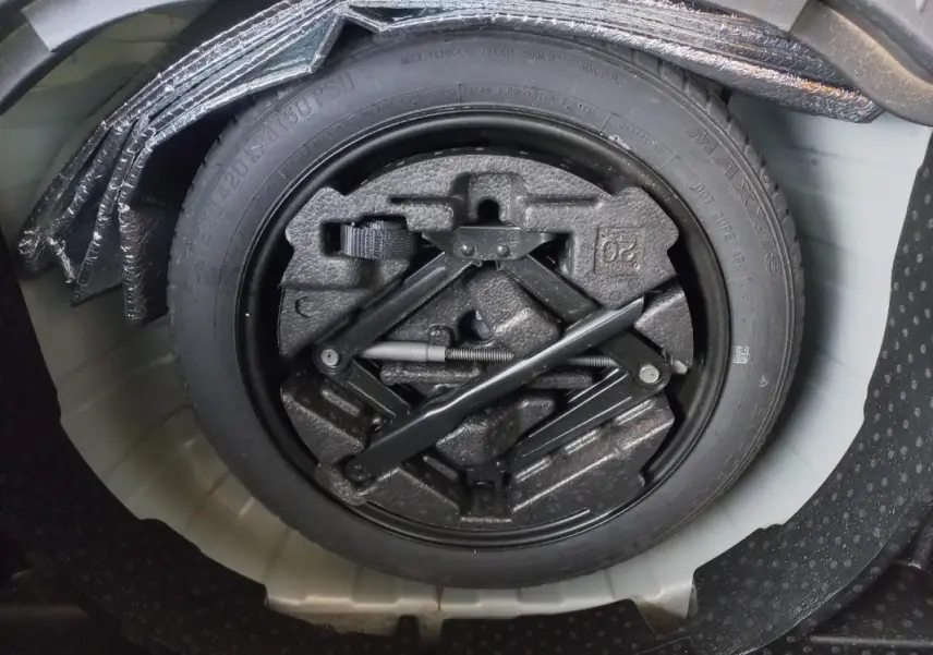 Roue de secours avec outillage intégré dans le coffre d'un Opel Mokka X gris 2017, vue en plongée.