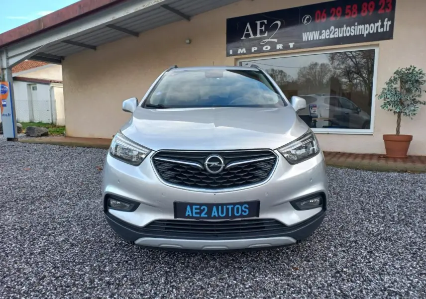 Vue avant d'un Opel Mokka X gris 2017, avec calandre noire et plaque AE2 AUTOS visible.