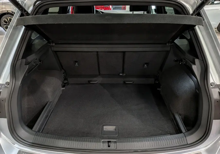 Coffre ouvert vu de l'arrière d'un Volkswagen Tiguan 1.5 TSI R-Line reflet d'argent, espace de chargement spacieux et tapis noir.