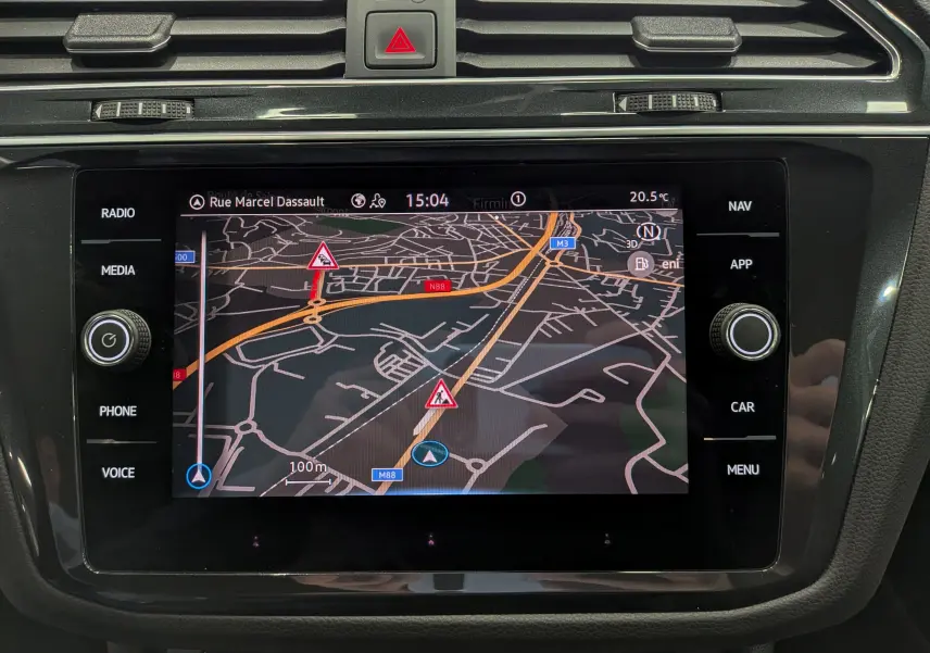 Écran tactile central du Volkswagen Tiguan 2024 en reflet d'argent, affichant la navigation avec carte et alertes trafic.