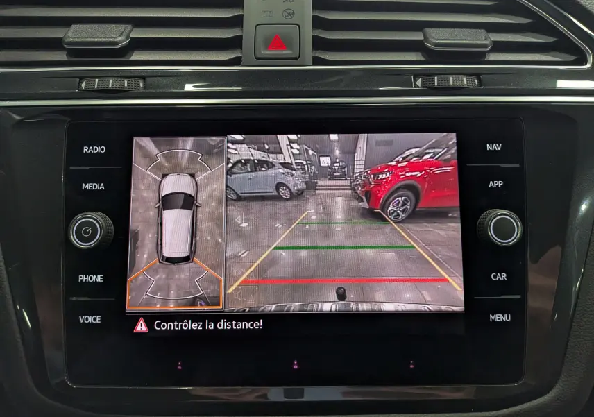 Écran de caméra de recul du Volkswagen Tiguan 2024 en reflet d'argent, affichant vue arrière avec lignes de guidage colorées.