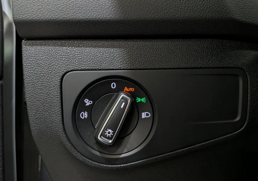 Gros plan sur le sélecteur de phares du Volkswagen Tiguan 2024, avec éclairage automatique activé, intérieur noir texturé.