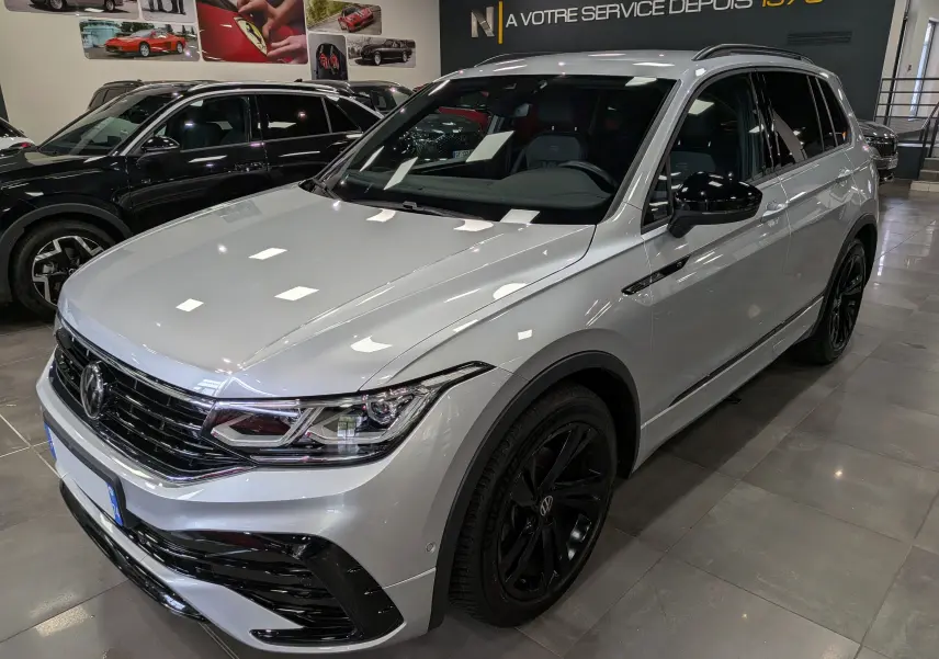 Volkswagen Tiguan 1.5 TSI R-Line reflet d'argent vu en 3/4 avant droit avec jantes noires et détails noirs contrastants.