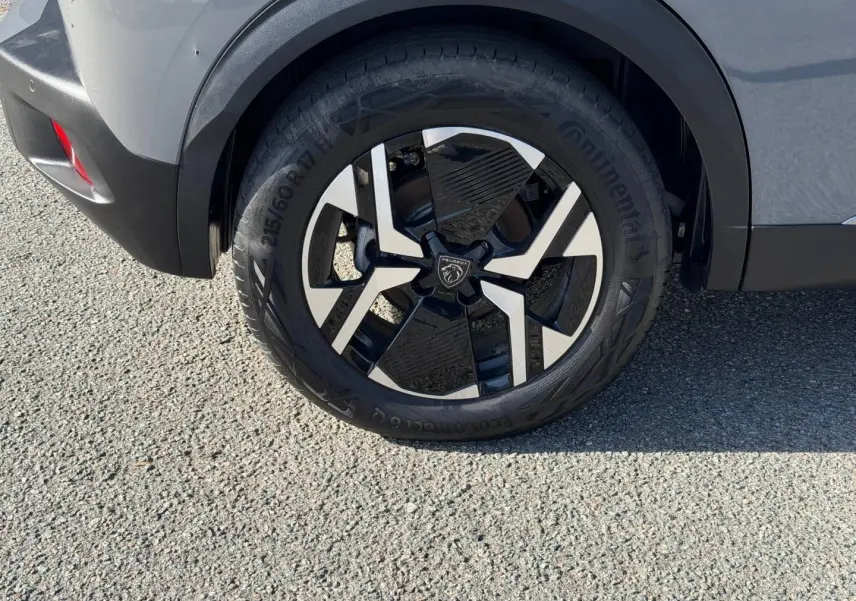 Gros plan sur la roue arrière droite avec jante alu bicolore du Peugeot e-2008 gris Artense 2025.